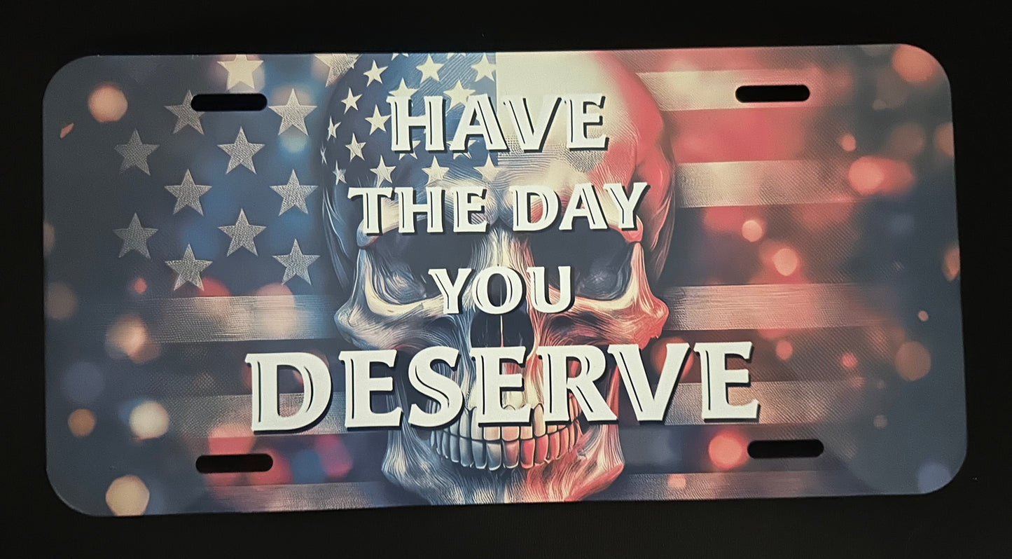 License plate with skull design and text 'Have the day you deserve' on an American flag background.