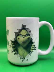 White ceramic mug with a green Grinch-like character tearing through torn paper on a bright green background.
