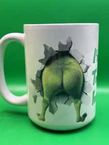 White ceramic mug featuring a green creature breaking through a cracked wall on a bright green background.