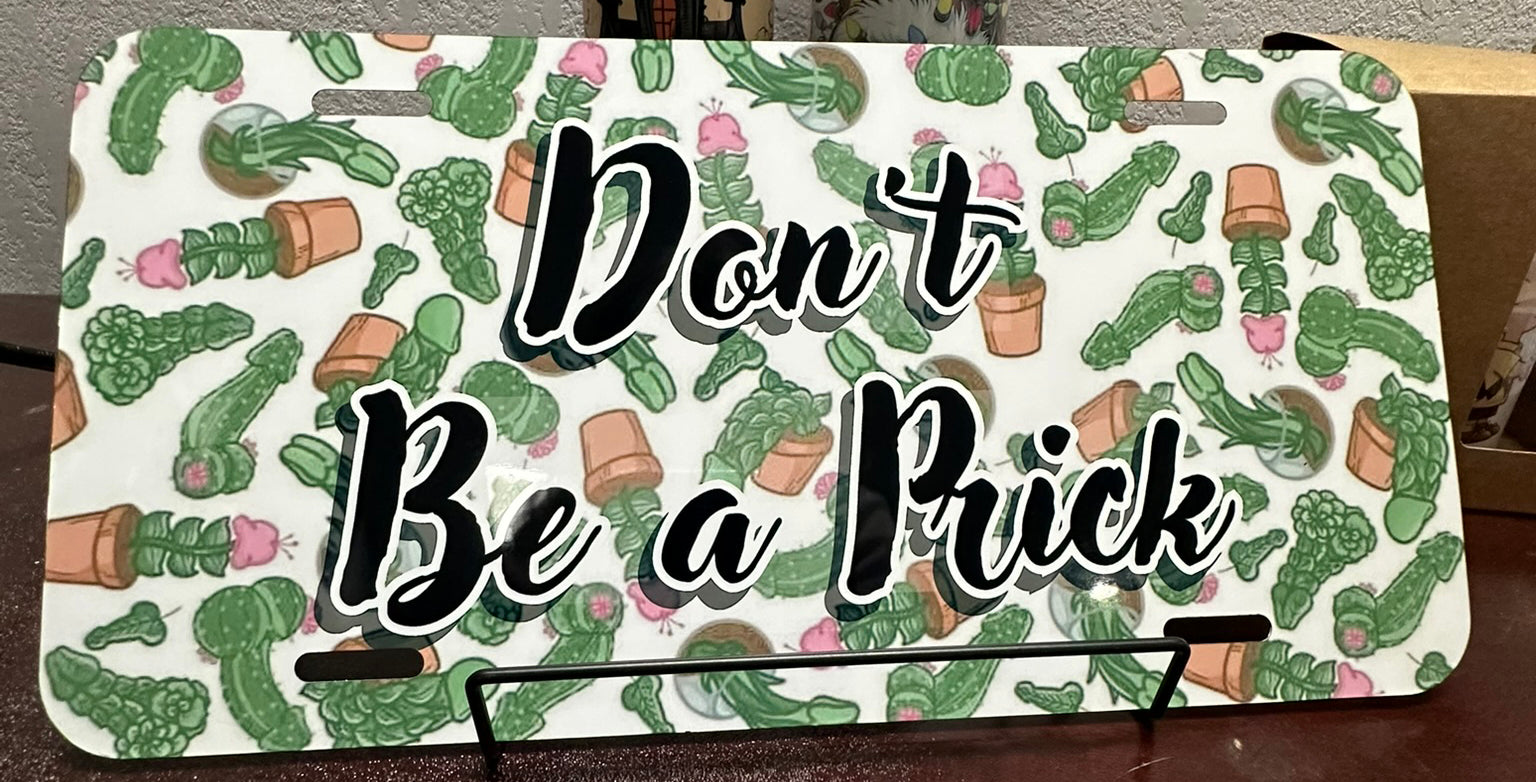 License plate with cactus pattern and text 'Don't Be a Prick' on a white background.