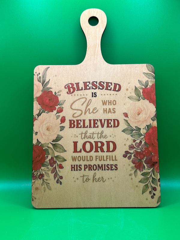Wooden cutting board with floral design and inspirational quote on a green background